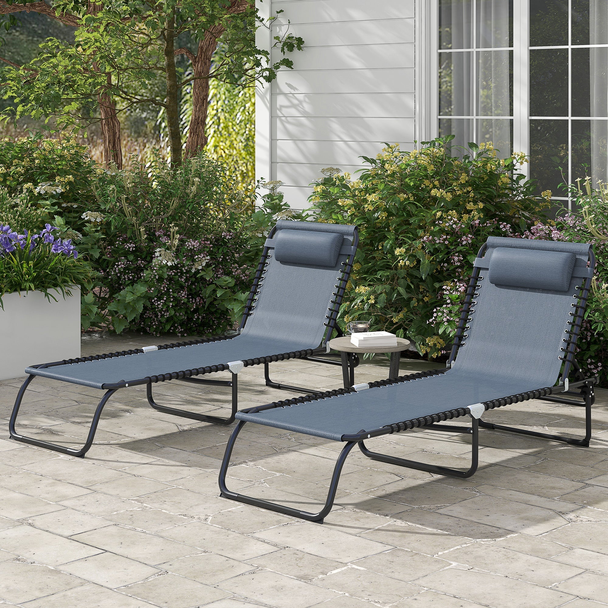Two gray folding chaise lounge pool chairs with adjustable reclining backs and pillows on patio