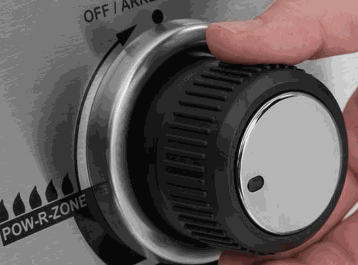 Close-up of hand adjusting the control knob on Broil King CROWN 520 grill featuring professional-grade performance and durable design