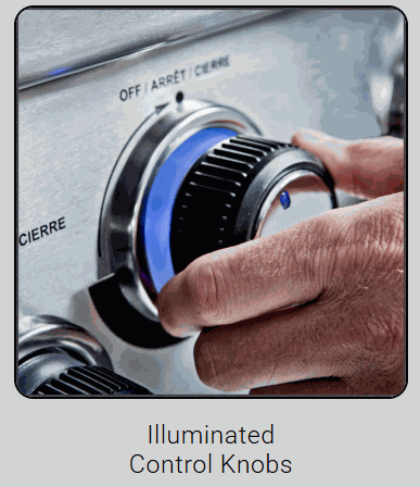 Close-up of hand adjusting illuminated control knob on Broil King Baron 590i grill with stainless steel panel