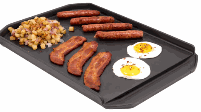 Cast iron plancha griddle cooking bacon, sausages, eggs, and potatoes with tall sides and grease trough designed for Broil King BBQ grills