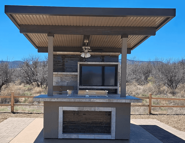 Customizable Baja Outdoor Kitchen Island with built-in BBQ grill, patio cover, outdoor TV, refrigerator, gas fire feature, and bar seating